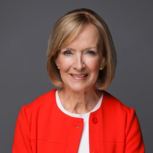 Photo Judy Woodruff wearing a red sweater on a gray background 