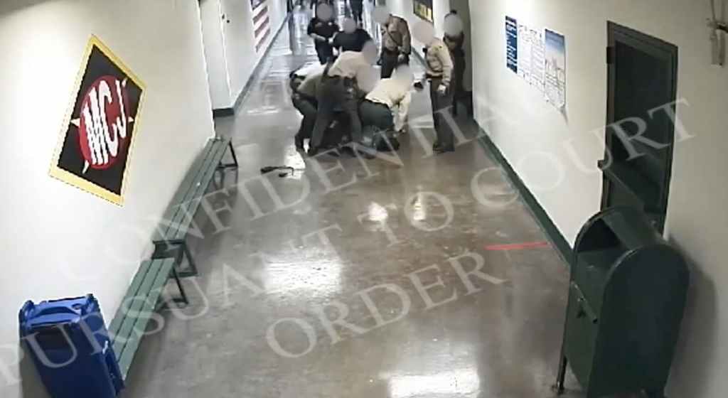 A screen capture from one of several unsealed surveillance videos shows sheriff's deputies kneeling on an inmate's neck inside a Los Angeles County jail.