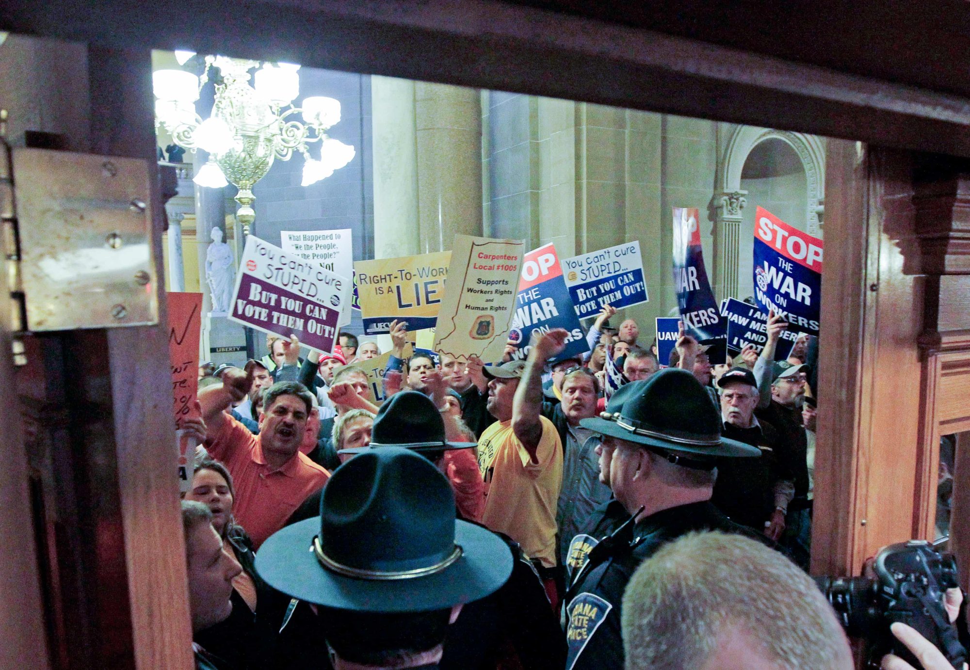 In this Jan. 25, 2012, file photo, Indiana State Police stand at the entrance of the House of Representatives during a debate on the right to work bill at the Statehouse in Indianapolis. As indiana prepares to become the first state in a decade to adopt the right-to-work law, the argument over exactly what the measure means for a state's economy is likely to rage on, unresolved, as it has for 70 years. (AP Photo/Darron Cummings, File)