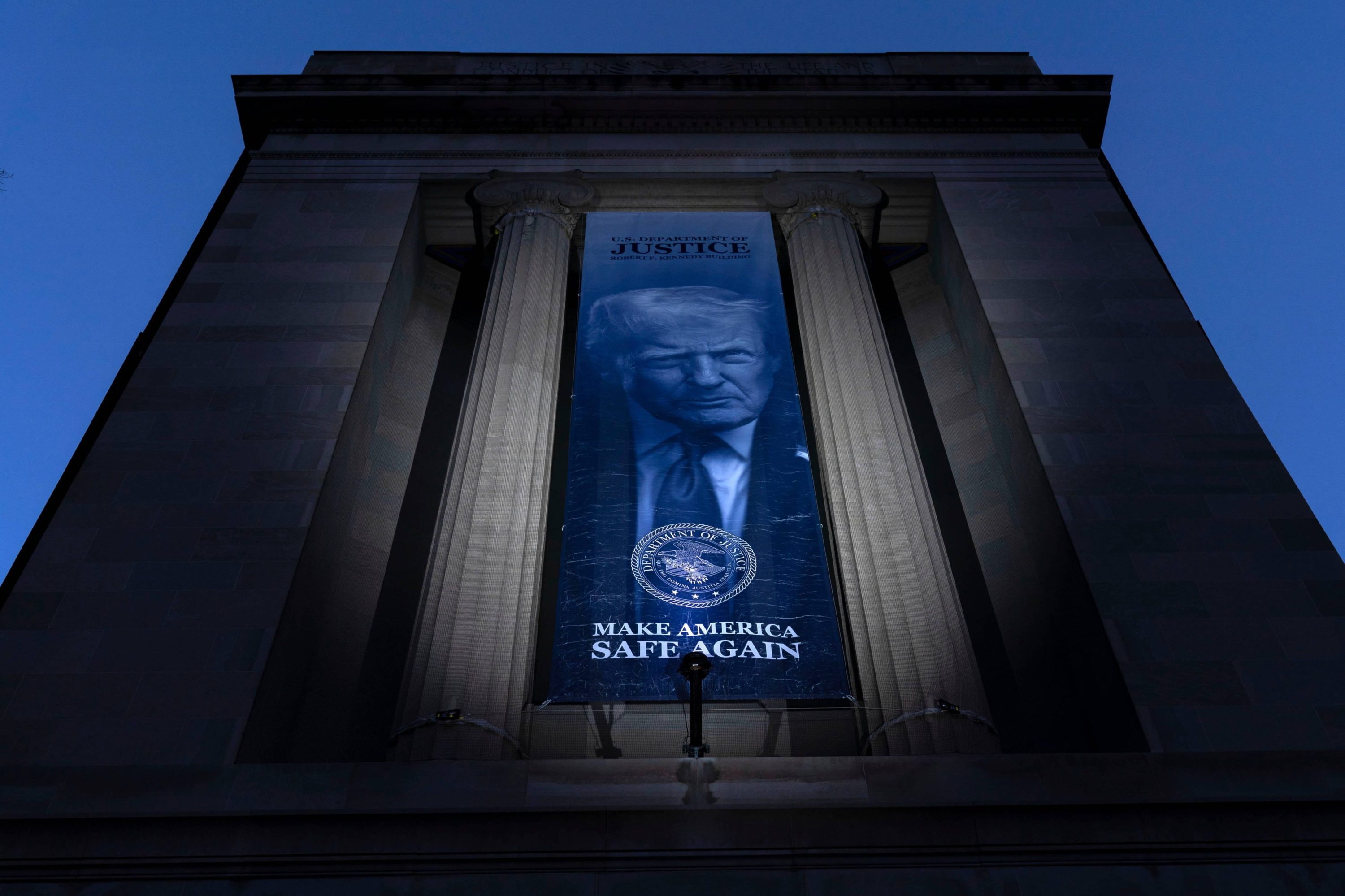 A banner with a portrait of President Donald Trump is hung from the Department of Justice, Saturday, March 7, 2026, in Washington. (AP Photo/Jose Luis Magana)