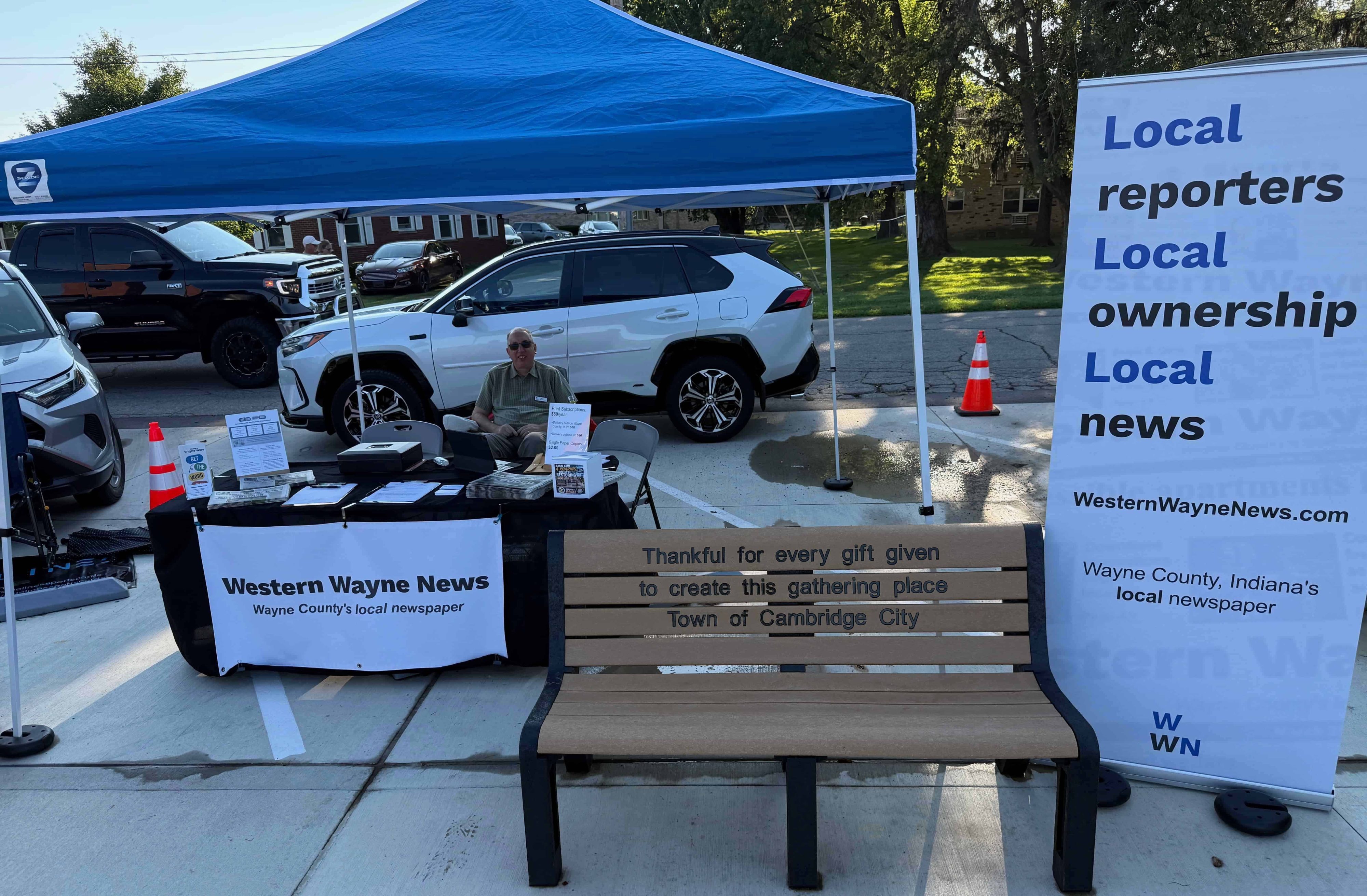 Reporter Mike Emery greets readers at the Western Wayne News tent during a community flood relief benefit event in Cambridge City, Indiana, on Sept. 4, 2026. (Chris Hardie/Western Wayne News)